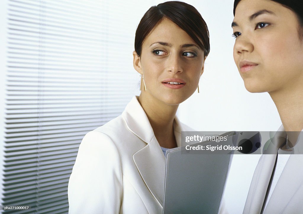 Two businesswomen standing together looking to the side