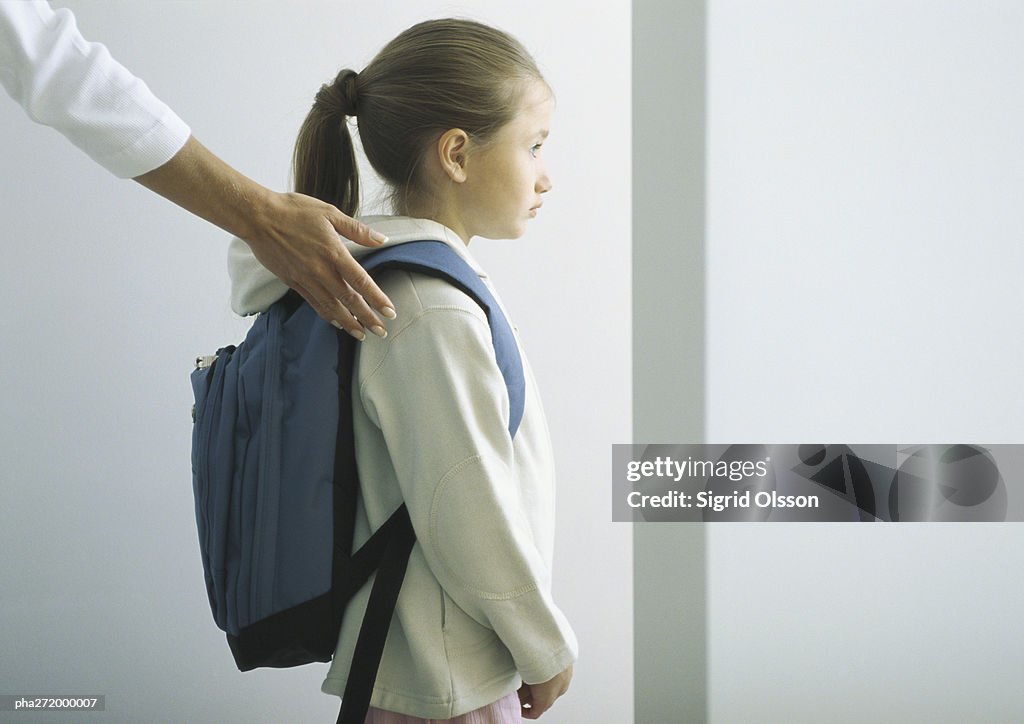 Woman's hand on shoulder of girl with backpack