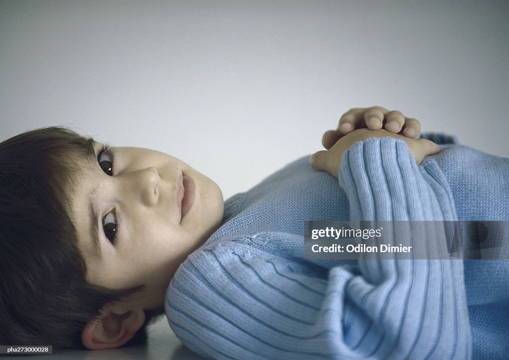 Boy lying down with hands on chest