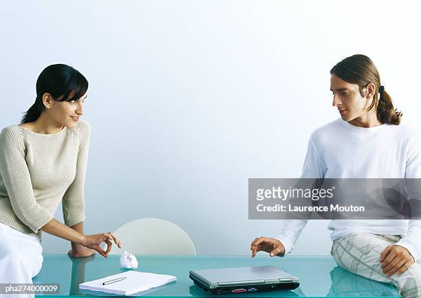 man and woman sitting on table, woman flicking paper ball to man - dare un colpetto foto e immagini stock