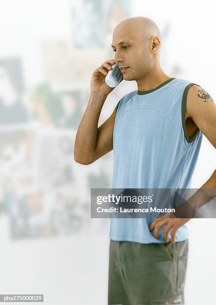 man with shaved head standing and talking on phone - shaved head ストックフォトと画像