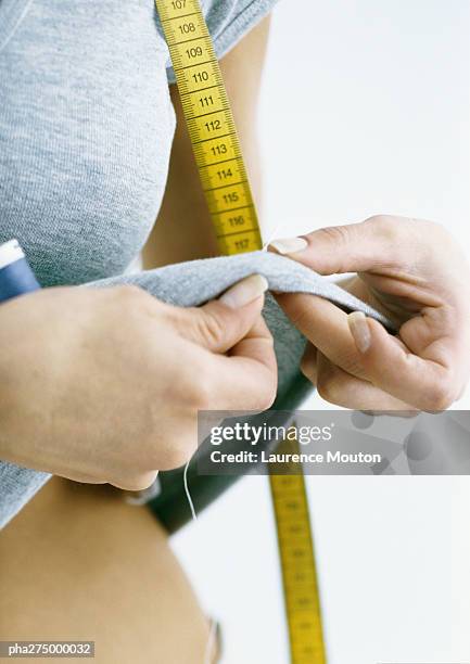 woman sewing on tee-shirt she is wearing, close-up - tee reel stock pictures, royalty-free photos & images