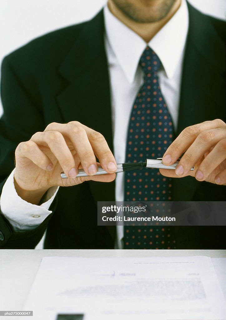 Businessman putting cap on pen, partial view