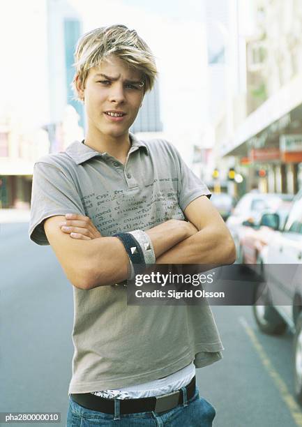 teenage boy standing in street with arms folded, portrait - body modification stock-fotos und bilder