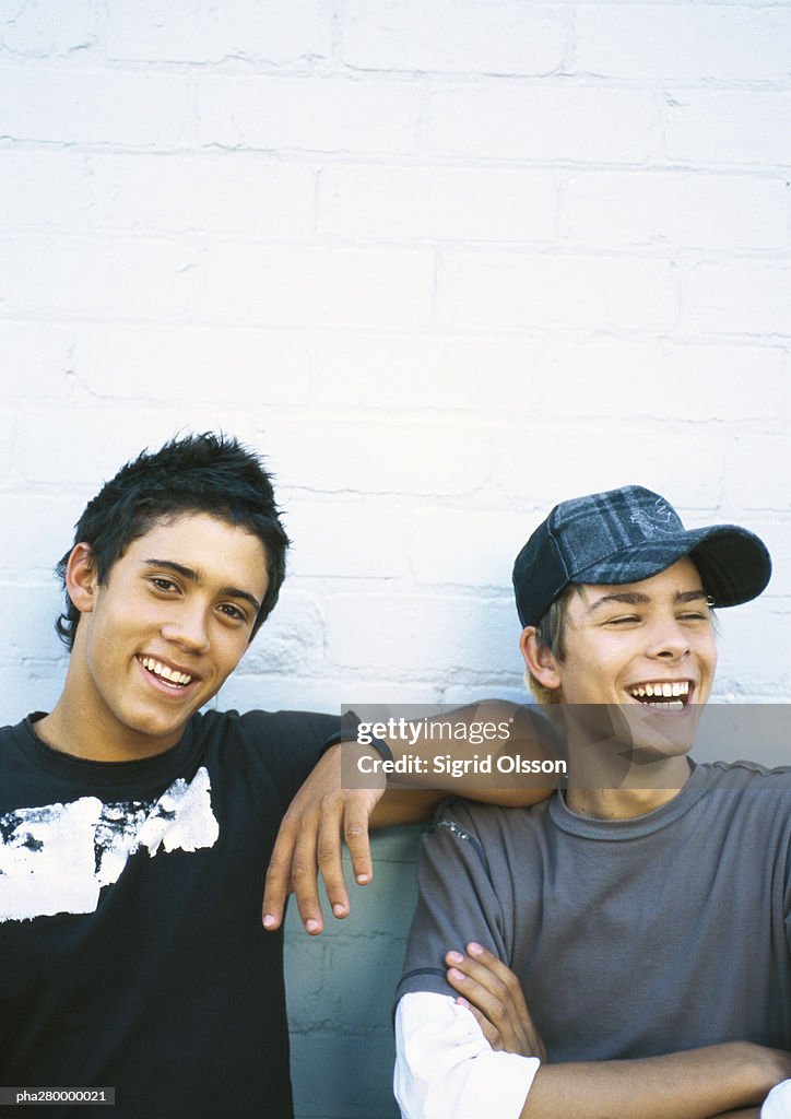 Two teenage boys leaning against brick wall, portrait