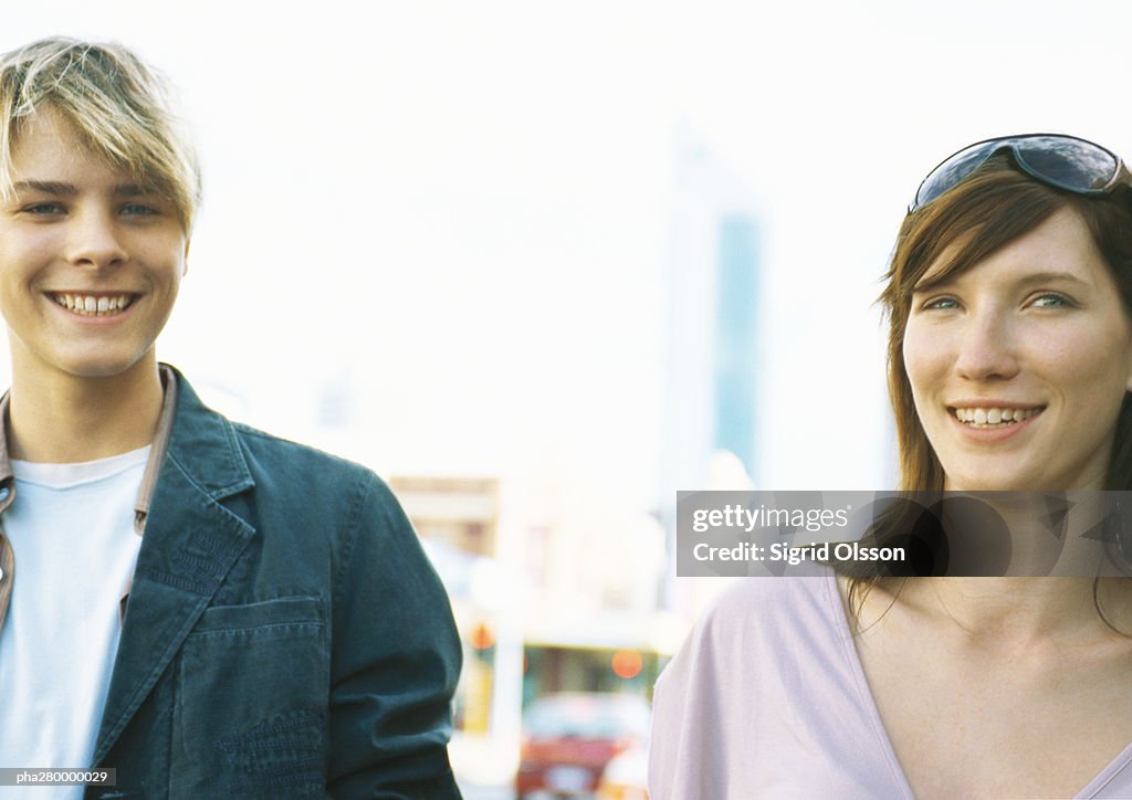 Young woman and teenage boy, smiling at camera