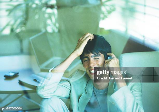 man smiling and using cell phone, seen through glass pane - gerrard stock-fotos und bilder