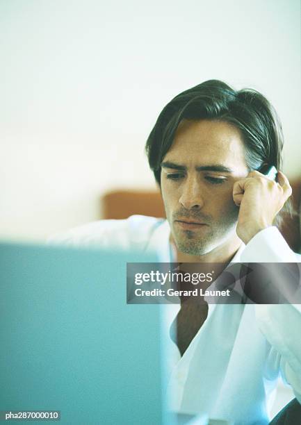 man with serious expression holding cell phone to ear - gerrard stock-fotos und bilder