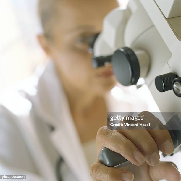 doctor looking through microscope - clinical study ストックフォトと画像