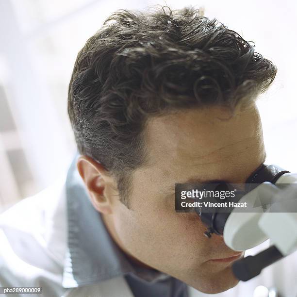 doctor looking through microscope - clinical study ストックフォトと画像