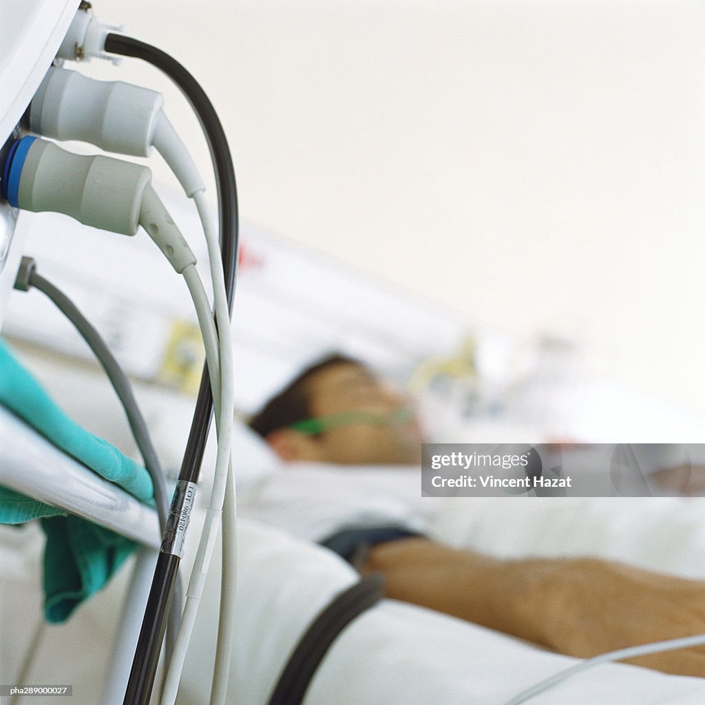 Patient in hospital bed and wires from monitor