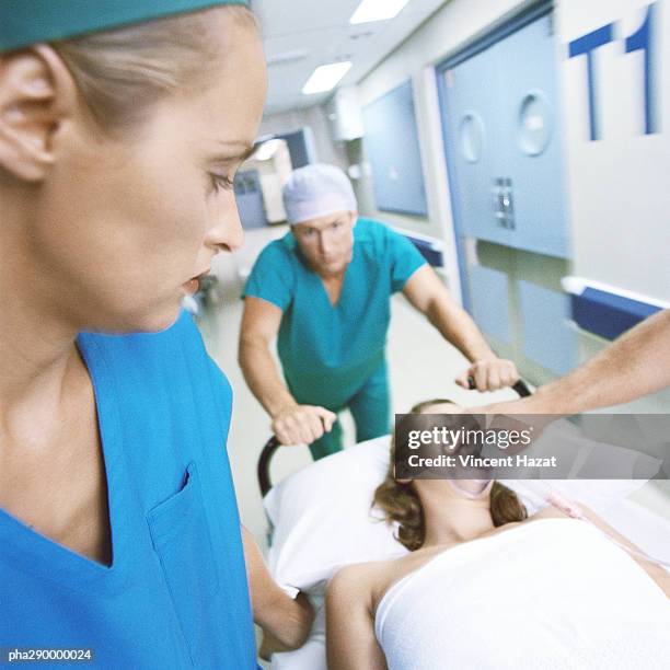 medical team pushing patient on gurney - chirurgenkappe stock-fotos und bilder