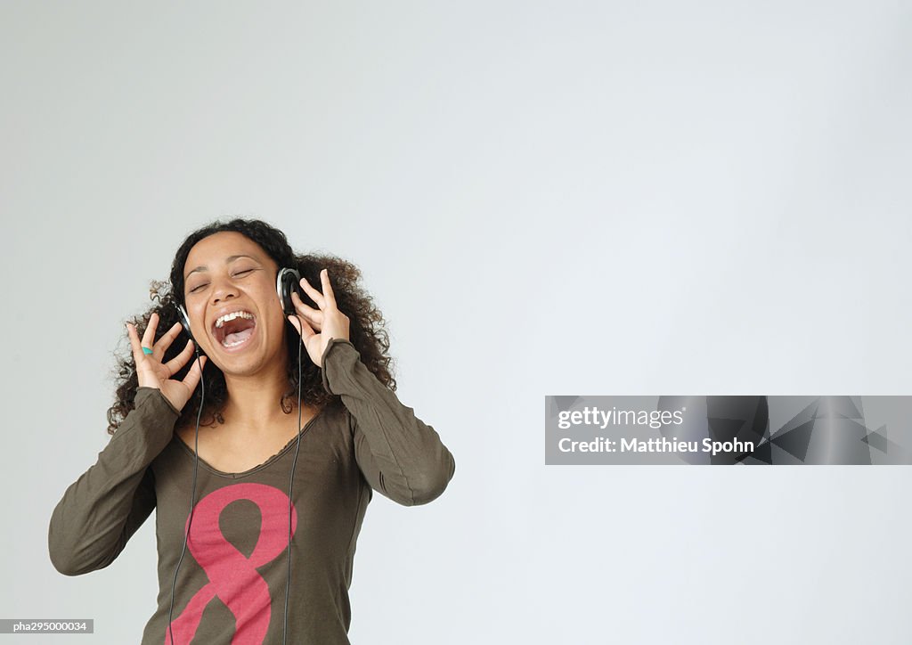Young woman listening to headphones, singing, portrait