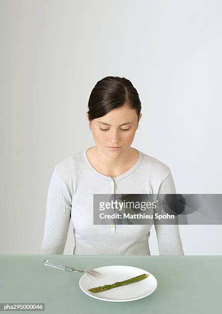young woman looking down at plate with single asparagus - asparagus photos et images de collection