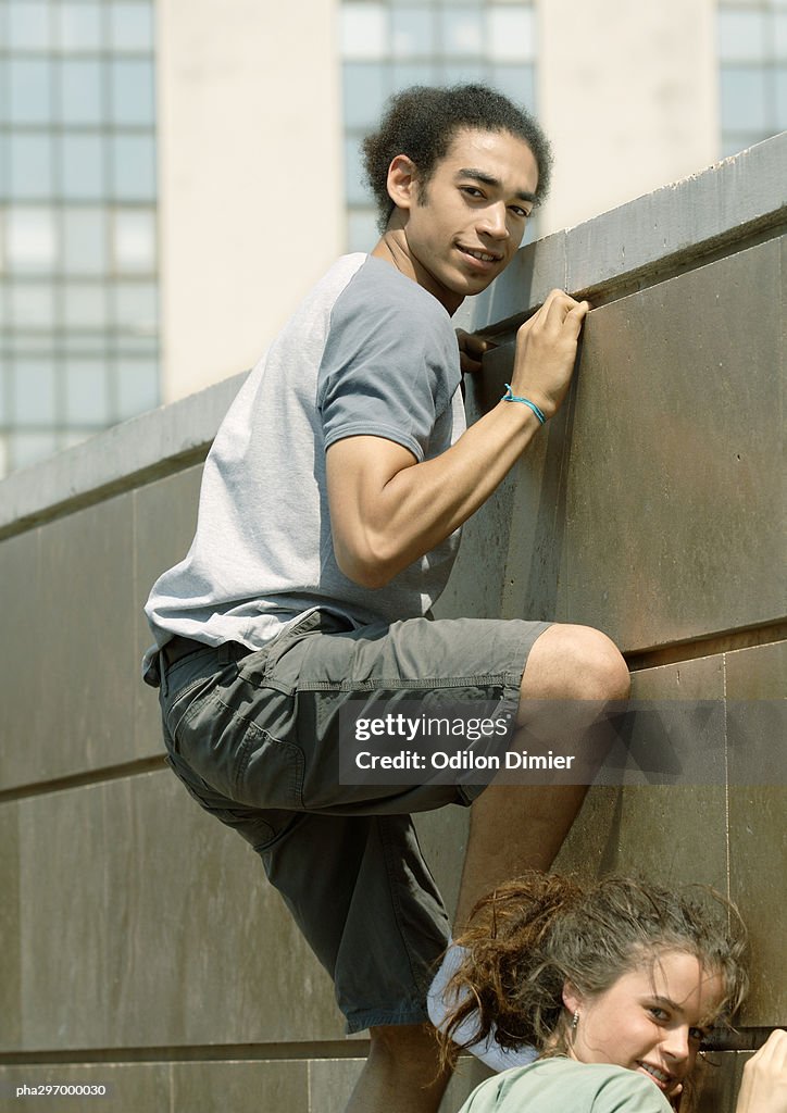 Young man and woman climbing wall