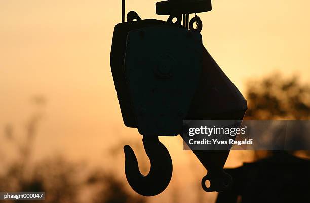 crane hook silhouetted at sunset - yves stock pictures, royalty-free photos & images