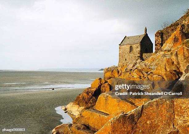 stone house on rocks overlooking beach - o foto e immagini stock