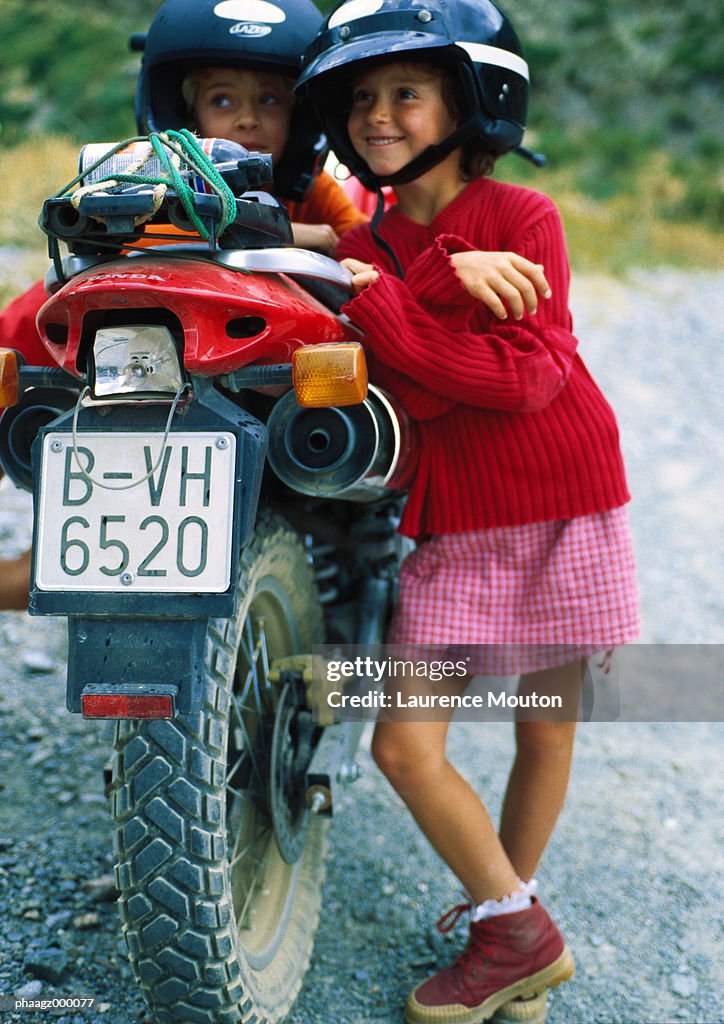 Two children leaning against motorbike