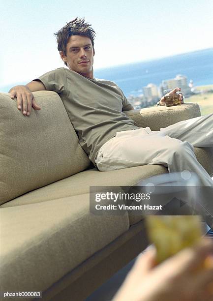 man sitting on sofa holding drink - verkeerde houding stockfoto's en -beelden