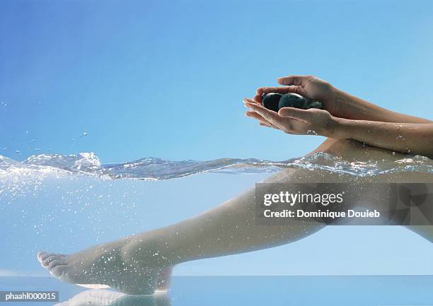 woman's legs in water and hands holding stones - balneotherapy stock pictures, royalty-free photos & images