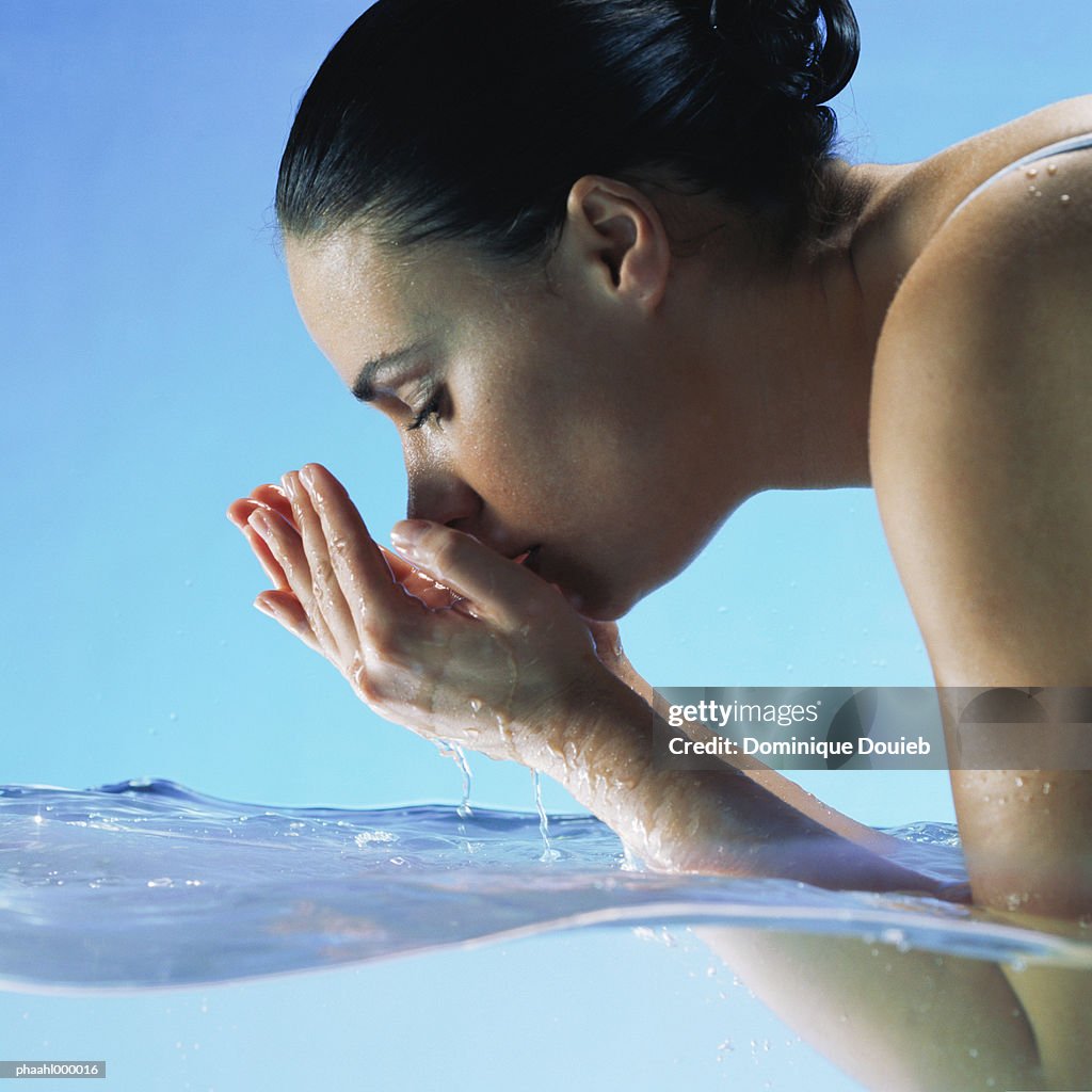 Woman in water cupping hands to face