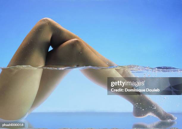 woman's bare legs crossed in water - balneotherapy stock pictures, royalty-free photos & images
