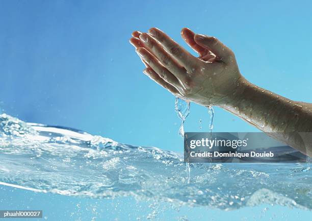 woman's hands cupped and dripping above water surface, side view - balneotherapy stock pictures, royalty-free photos & images
