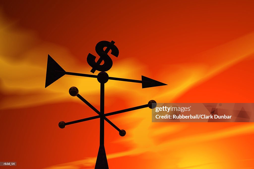 Money symbol weathervane is silhouetted against an orange sky