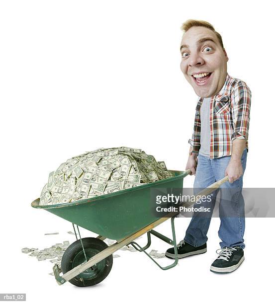 conceptual caricature of a caucasian man in work clothes as he pushes a wheelbarrow full of money - cash wheelbarrow stock pictures, royalty-free photos & images