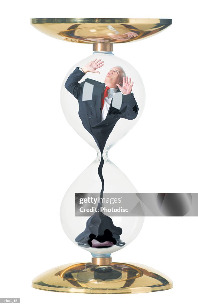 Conceptual photo of a caucasian business man in a suit as he is stuck in and sucked through an hourglass
