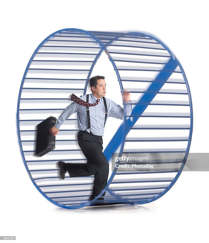 A caucasian businessman in a shirt and tie as he runs around in circles in a hamster wheel