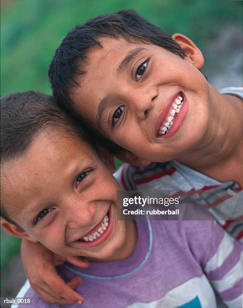 two young latin american boys with their arms around each other are smiling up into the camera in costa rica - costa stock pictures, royalty-free photos & images