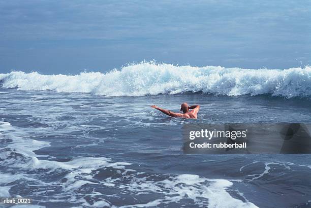 a bald man is swimming in the ocean waves in costa rica - costa stock pictures, royalty-free photos & images