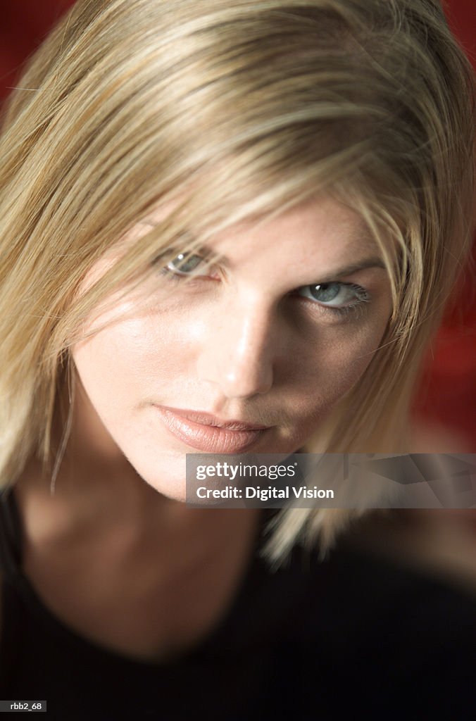 Close up portrait of a young caucasian blonde woman in a black tank top as she seriously looks up into the camera