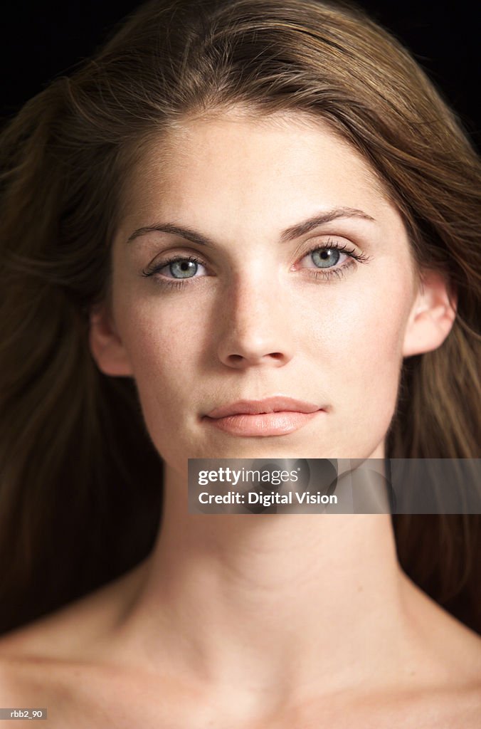 Portrait of attractive caucasian woman with blue eyes and hair flowing in wind looks at camera