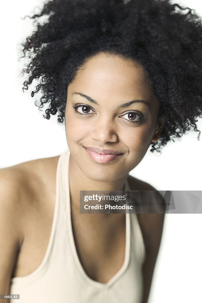 Close up shot of a young african american woman in a tan tank top as she smiles
