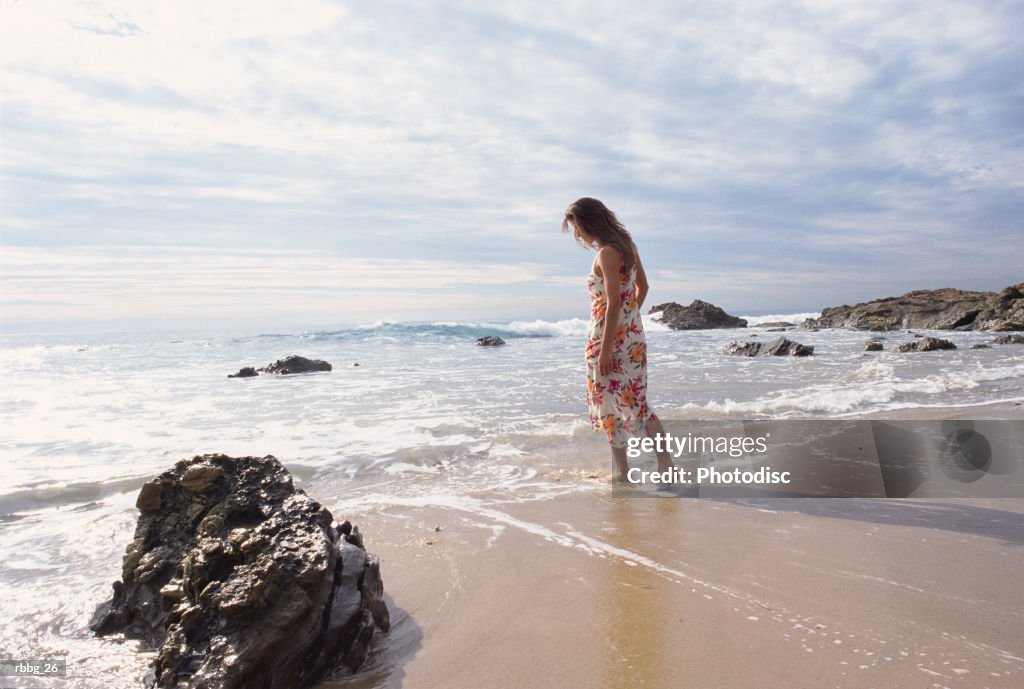 Girl in dress walking along the beach on a cloudy afternoon