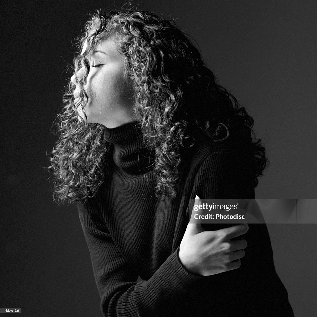 A side profile of a young caucasian woman whose face is obscured my her long curly hair