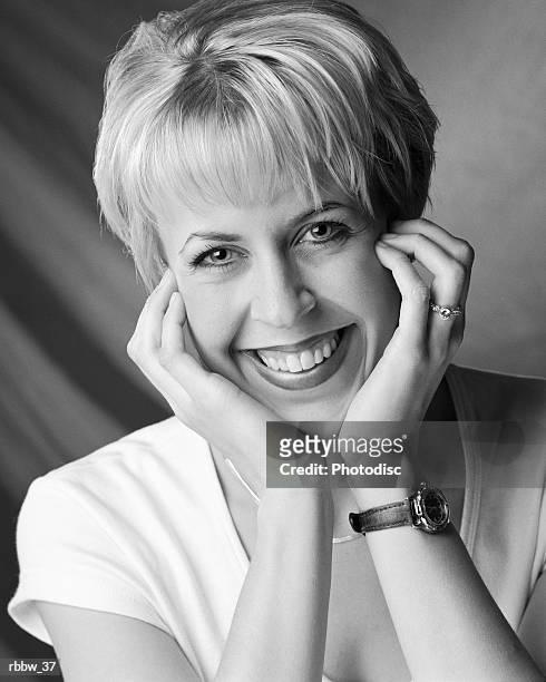 a happy blonde woman with her hands at her chin smiles big - happy stockfoto's en -beelden