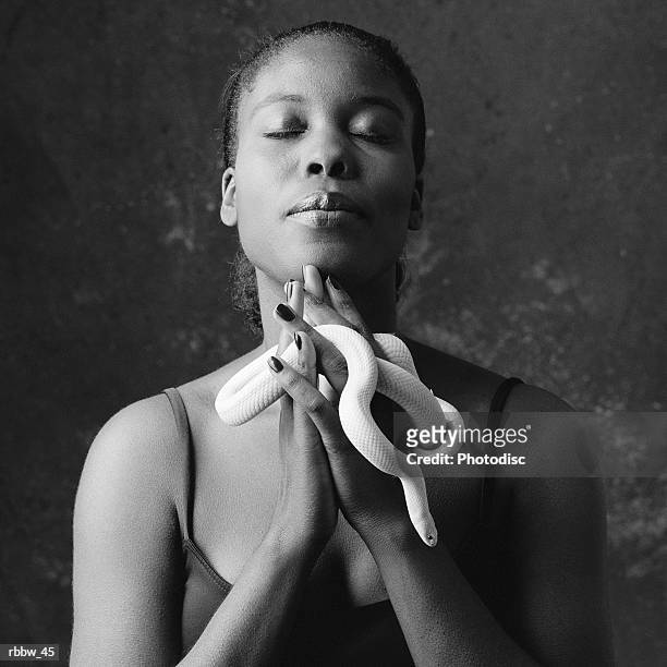 an african american woman holds a white snake in a prayer pose - portrait chantier stock-fotos und bilder