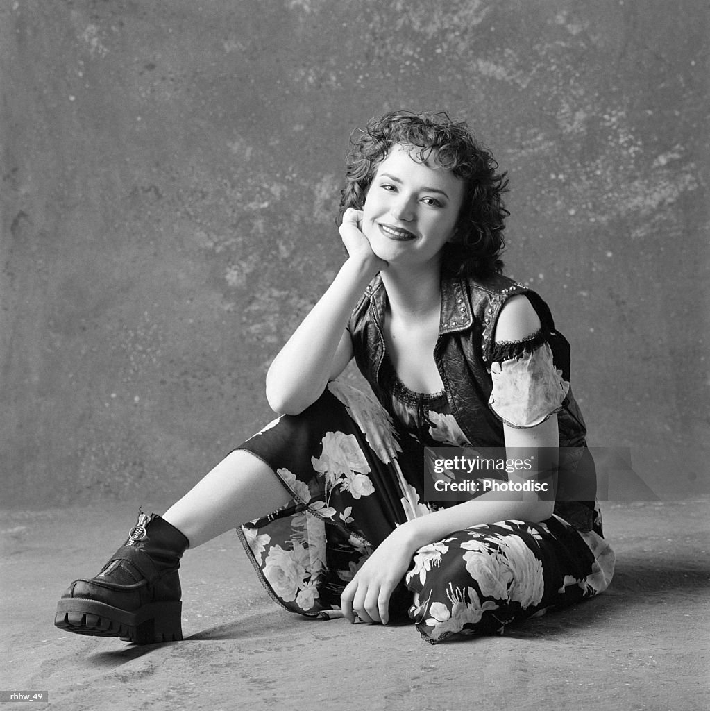 A spunky caucasian girl sits on the floor and smiles