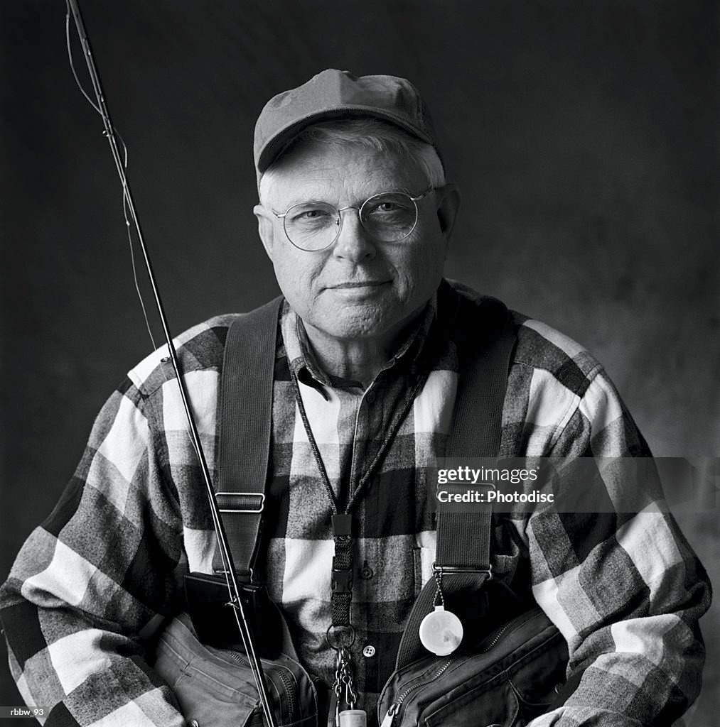 A caucasian elderly man sits in his fly fishing gear