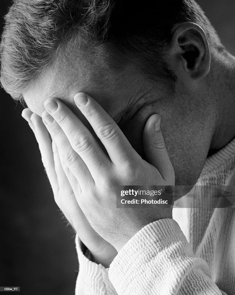 A caucasian man holds his face in his hands