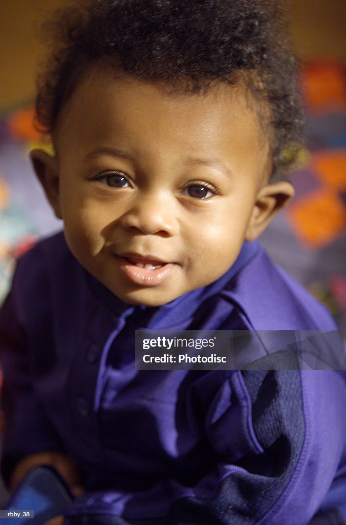 An african american baby looks up and playfully smiles