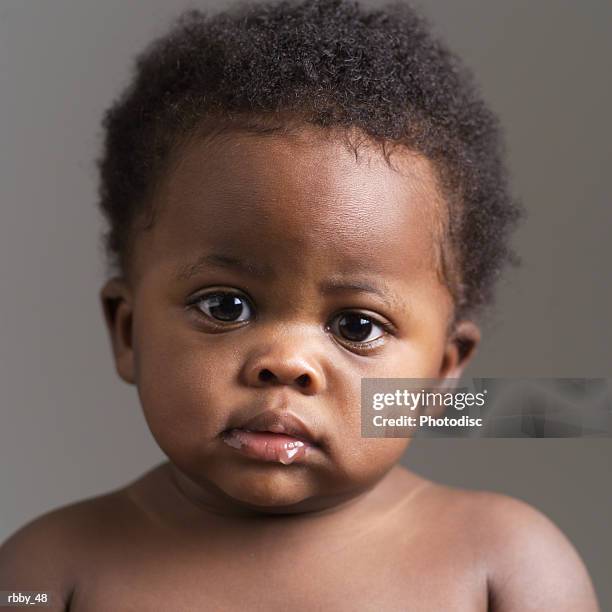 a shirtless african american baby looks solemnly into the camera - baby spit up stock-fotos und bilder