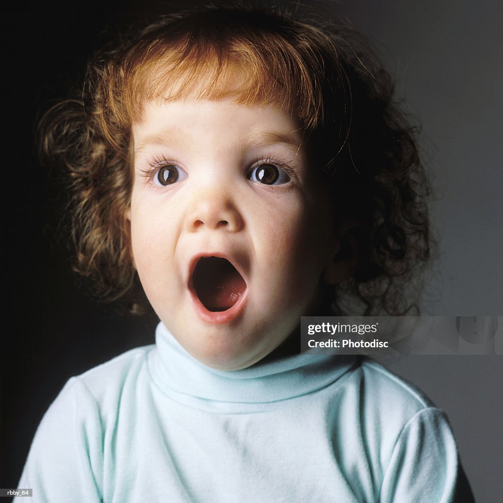 A redheaded caucasain toddler drops open her mouth in extreme surprise