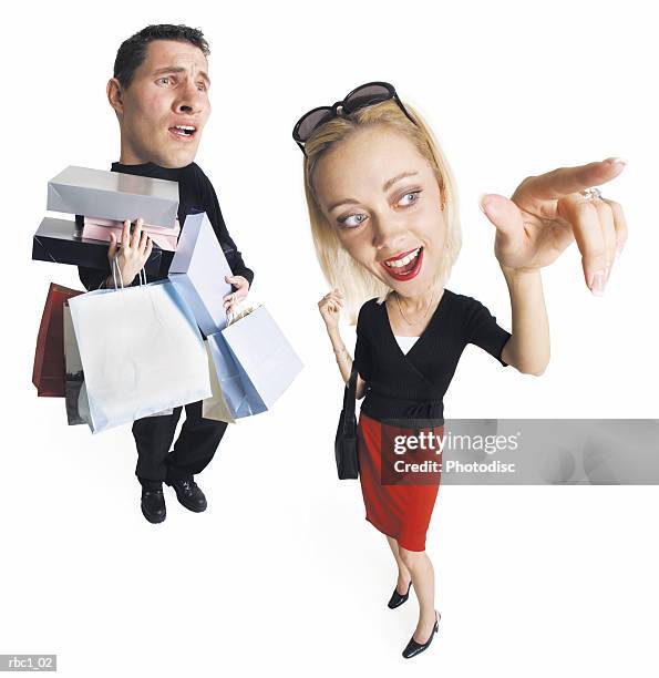 caricature young caucasian couple shopping the man carries many bags packages as blonde woman points - caricature 個照片及圖片檔