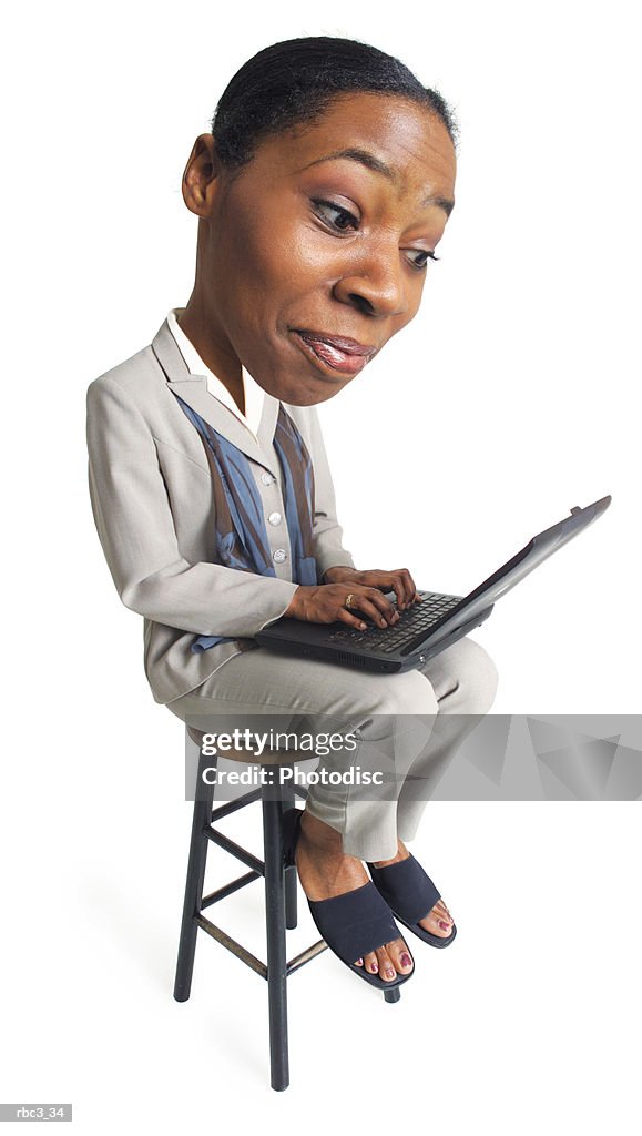 A young african american business woman sits with a computer on her lap and types away