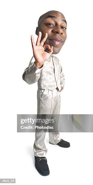 a young bald african american man wearing a champagne colored outfit stands while holding up one hand to make an o.k. sign - make up ストックフォトと画像