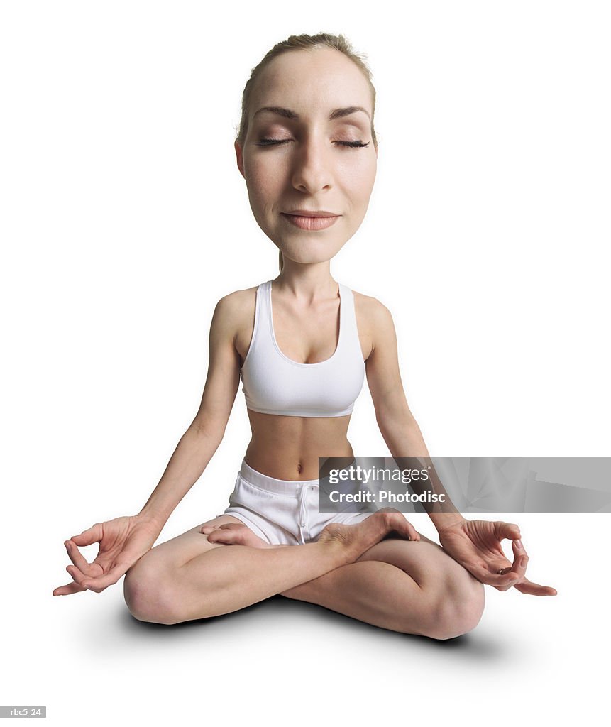 A young caucasian female wearing white work out clothes sits with her eyes closed and her legs crossed with her hands poised on her knees to meditate